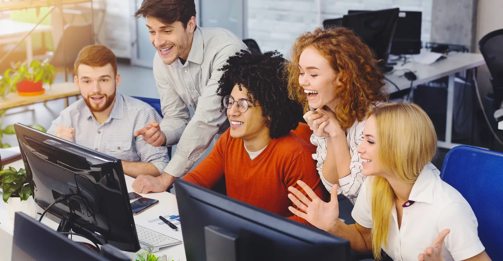 A team celebrating good news around a computer screen